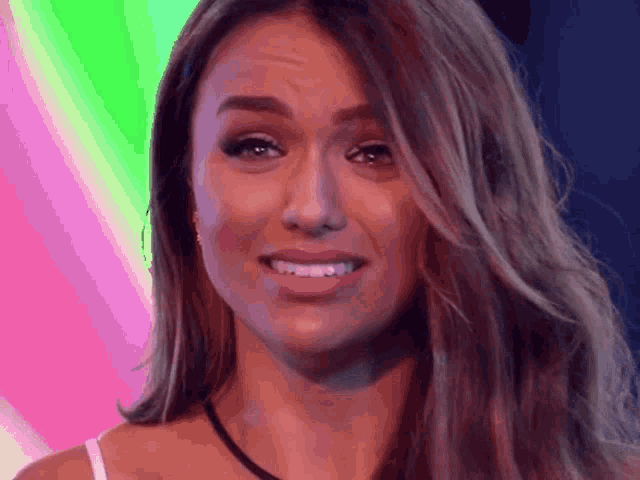 a woman with long hair is smiling in front of a rainbow background