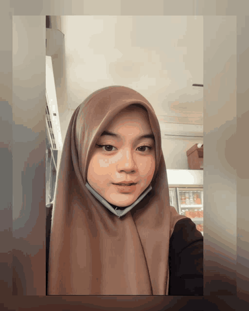 a woman wearing a hijab and a face mask poses for a picture