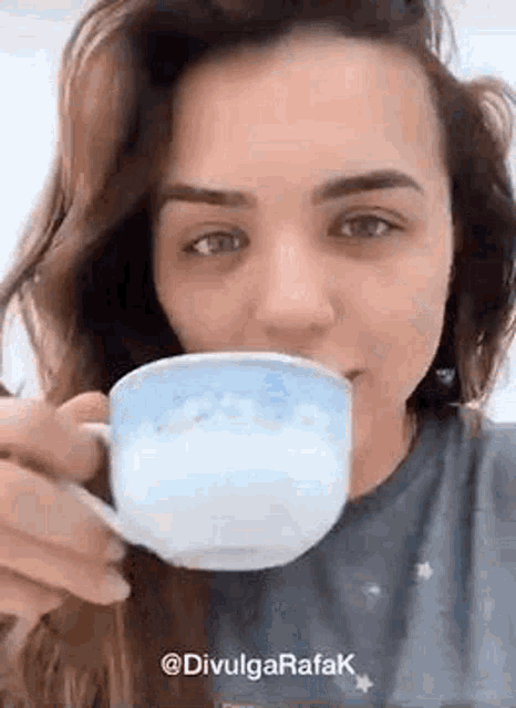 a woman is drinking a cup of coffee with milk .