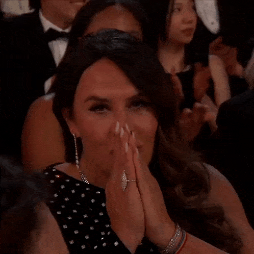 a woman in a black and white polka dot dress is clapping her hands