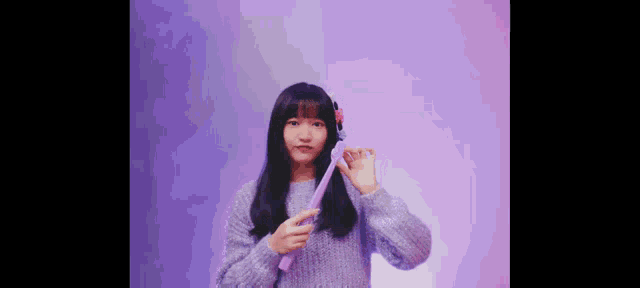 a girl in a purple sweater is holding a purple object in her hands .
