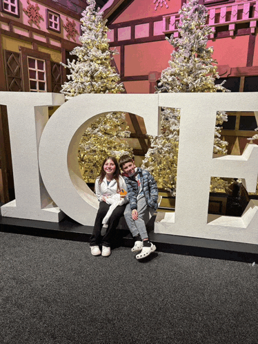 a boy and a girl sit in front of the word ice