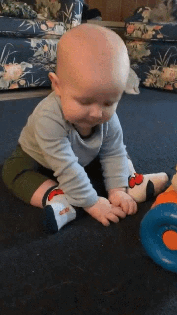 a baby wearing a pair of mickey mouse socks is sitting on the floor