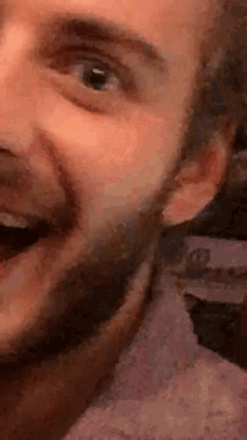 a close up of a man 's face with a beard smiling .
