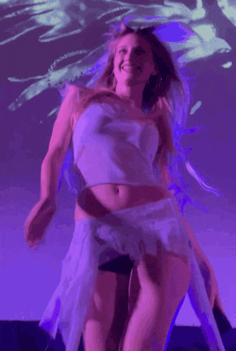 a woman dancing in front of a purple background