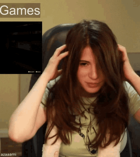 a woman is sitting in a chair with her hands on her head in front of a screen that says games