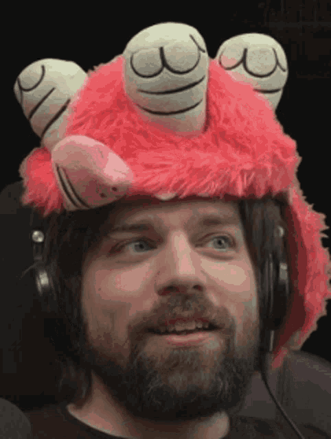 a man with a beard wearing headphones and a stuffed animal hat