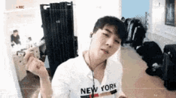 a man wearing a new york t-shirt is standing in a room with headphones on .