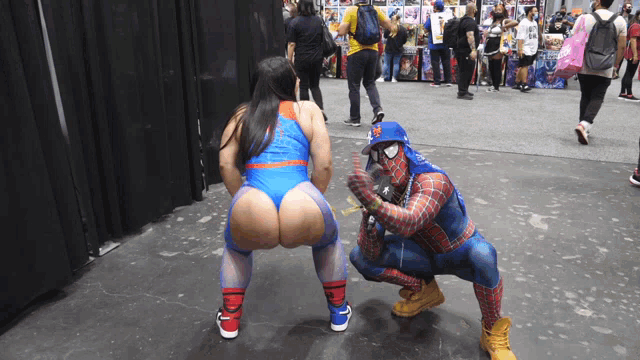 a man in a spiderman costume squatting next to a woman in a superhero costume