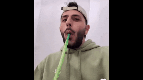 a man with a beard is smoking a hookah with a green hose in his mouth .