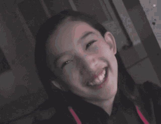 a little girl is smiling and looking at the camera .