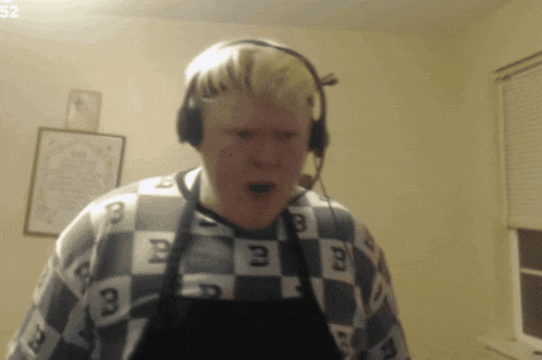 a man wearing headphones and a checkered shirt has the number 52 on the bottom