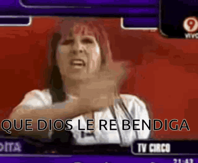 a woman with red hair is sitting in front of a tv screen and says que dios le re bendiga