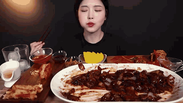 a woman is sitting at a table with a plate of food and chopsticks .