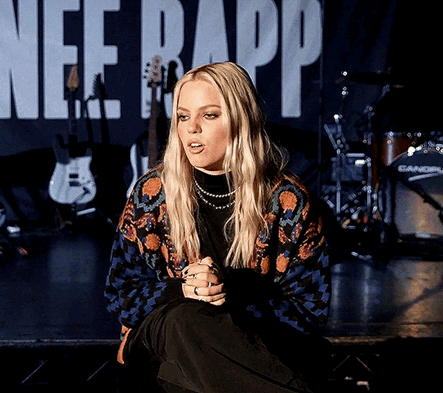 a woman is sitting on a stage in front of a banner that says nee rapp