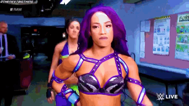 a woman with purple hair is standing in front of a wall that says raw on it
