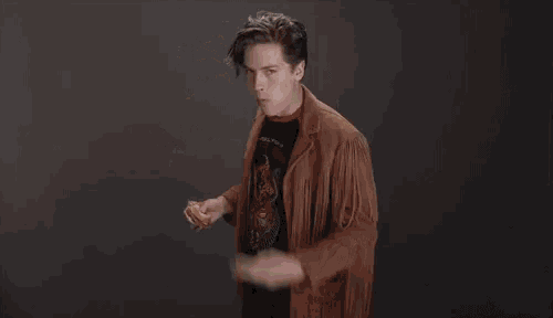 a young man in a fringed jacket is eating a sandwich and smoking a cigarette .