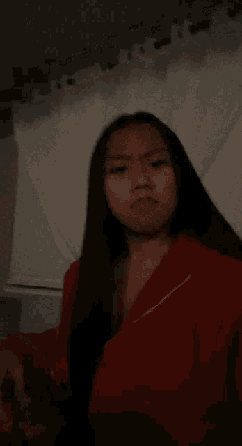 a woman with long black hair wearing a red jacket