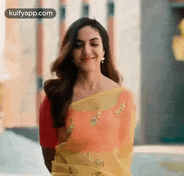 the woman is wearing a yellow saree and a red blouse .