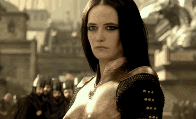 a woman in a gold armor stands in front of a crowd of people