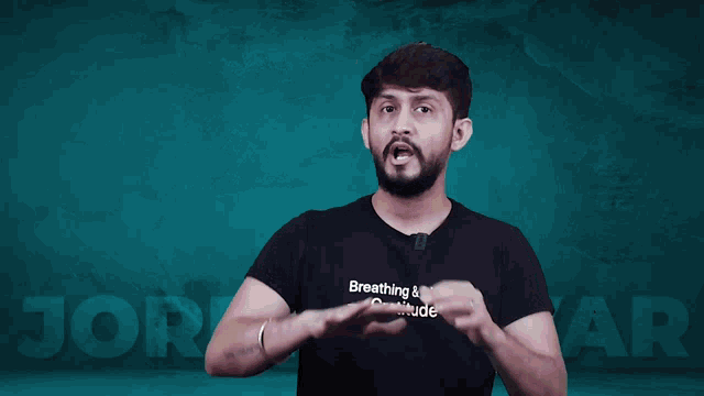 a man wearing a black shirt that says breathing & living gratitude