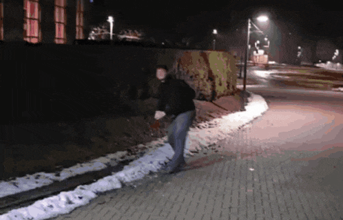 a man walking down a sidewalk at night