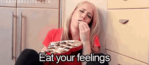a woman is sitting on the floor with a plate of chocolates and the words " eat your feelings " above her .