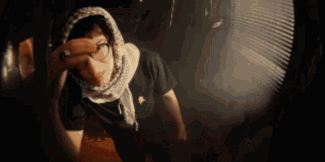 a man wearing a scarf covering his face is standing in the dark