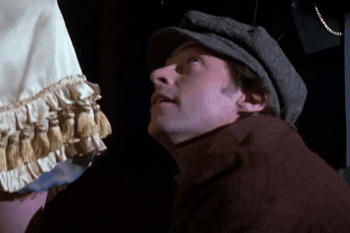 a man wearing a hat looks up at something in the dark
