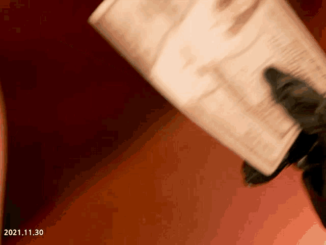 a blurred image of a person holding a piece of paper with the date 2021.11.30