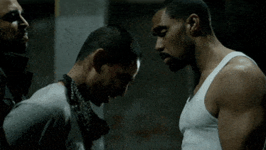 a man in a white tank top looks down at something