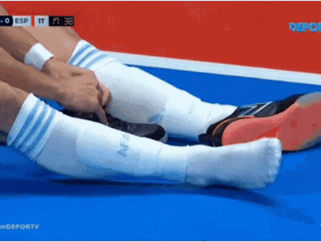 a soccer player wearing white socks with blue stripes is laying on the ground