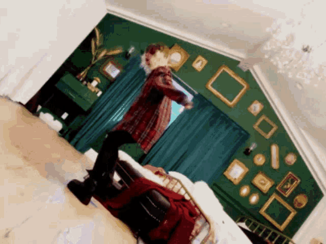 a man is dancing in a room with a green wall
