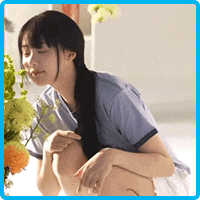 a woman in a blue shirt is kneeling down in front of a bouquet of flowers .