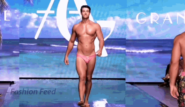 a man in pink swim trunks walks down the runway at a fashion show