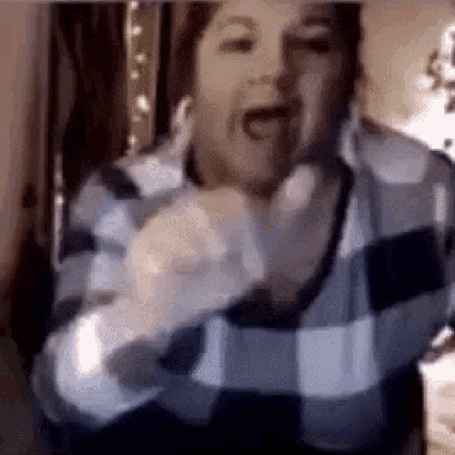 a woman in a plaid sweater is making a funny face while standing in front of a camera .