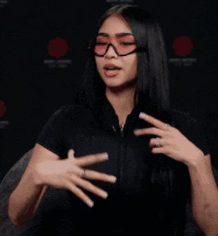 a woman wearing glasses and a black shirt holds her hair