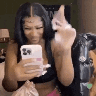 a woman is taking a picture of herself with her phone while sitting on a bed .