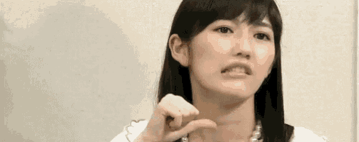 a woman with long black hair is making a funny face while pointing at herself .