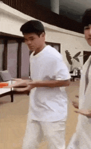 a man in a white shirt and white pants is walking in a living room .