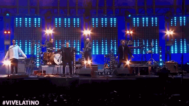 a group of men are playing instruments on a stage with #vivelatino written in the corner