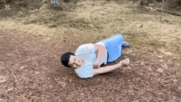 a man is laying on his stomach on the ground in a field .
