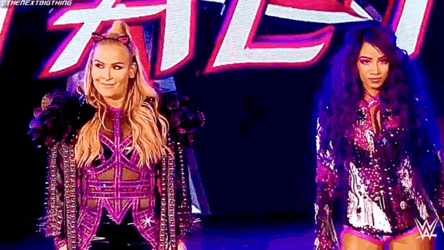 a couple of women standing next to each other on a stage in front of a sign .