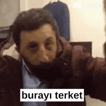 a man with a beard is making a funny face and says " burayi terket " on the bottom