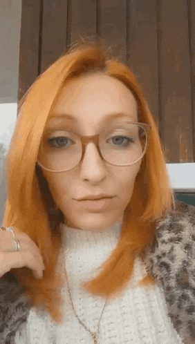 the woman is wearing glasses and a white sweater .