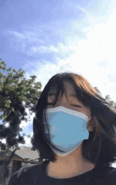 a young girl wearing a blue face mask against a blue sky