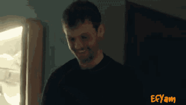 a man in a black shirt is smiling in front of a sign that says ecsam