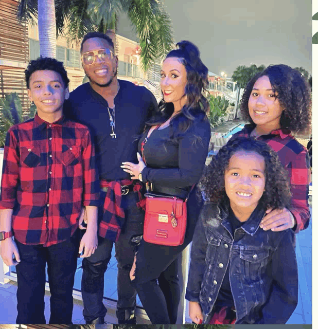 a family posing for a picture with a woman wearing a red purse that says ' chanel ' on it