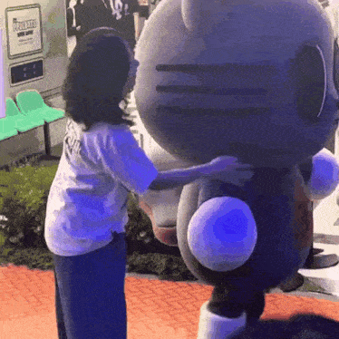 a hello kitty mascot is being hugged by a woman wearing a white shirt