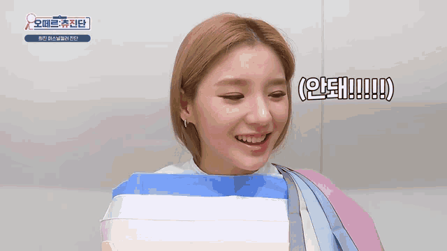 a woman wearing a blue and pink striped shirt is smiling with a foreign language sign above her
